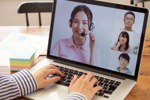 ノートパソコンの画面でビデオ通話をしている女性とその他の参加者